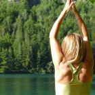 Back view of a woman meditating in a yoga pose by a serene lake in Ebensee, Austria.
